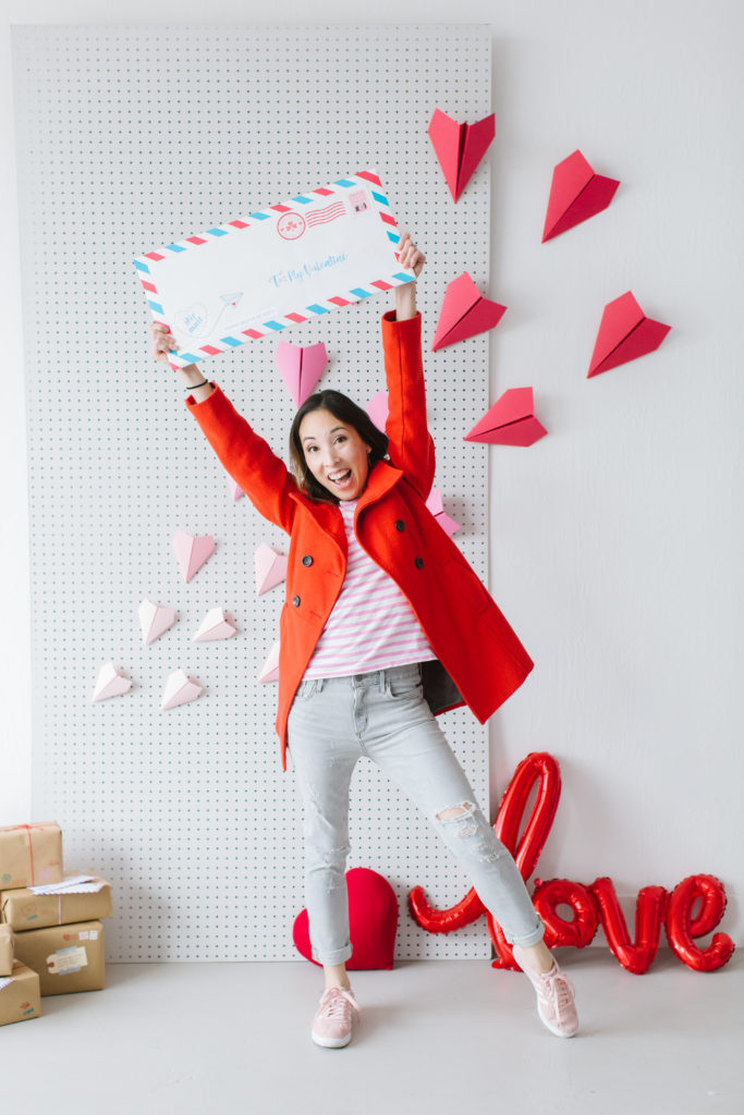 Valentine's Day photo shoot inspiration featuring giant love letter and paper airplane backdrop