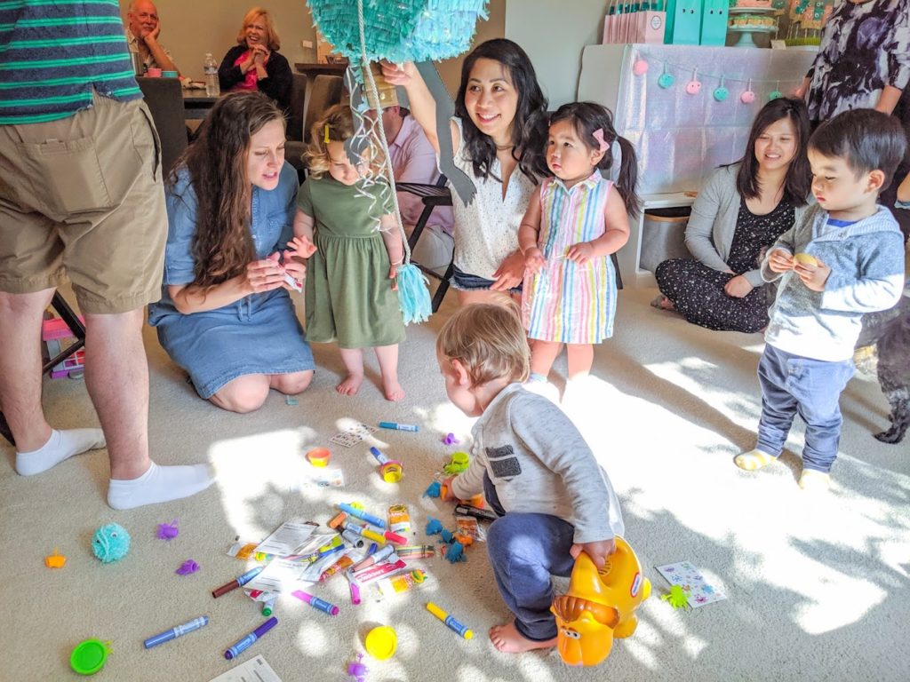 Toddlers picking out toys and treats from monster pinata