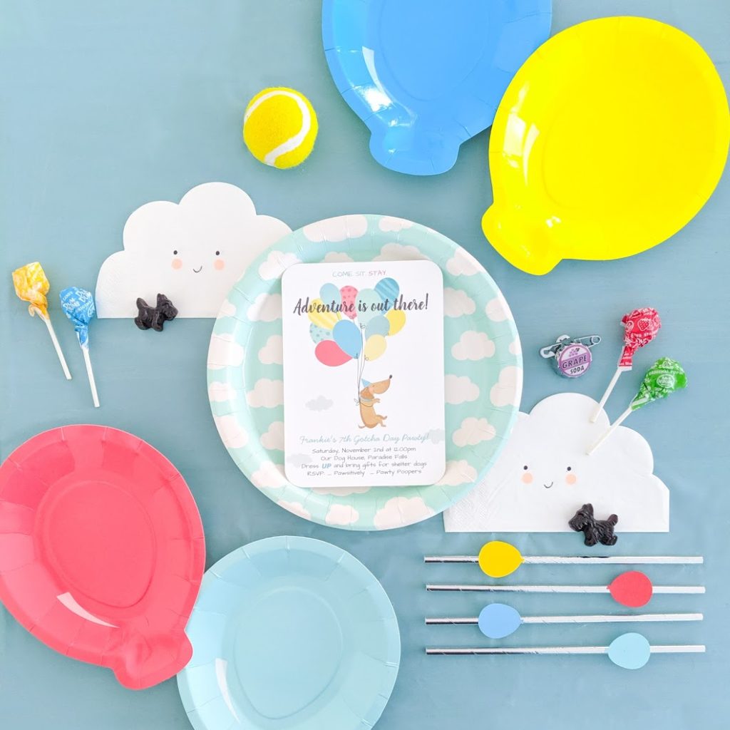 A display of dog party invitation, plates, napkins and straws