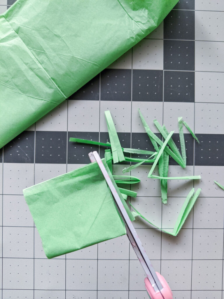 Cutting light green tissue paper into strips for Easter grass. 
