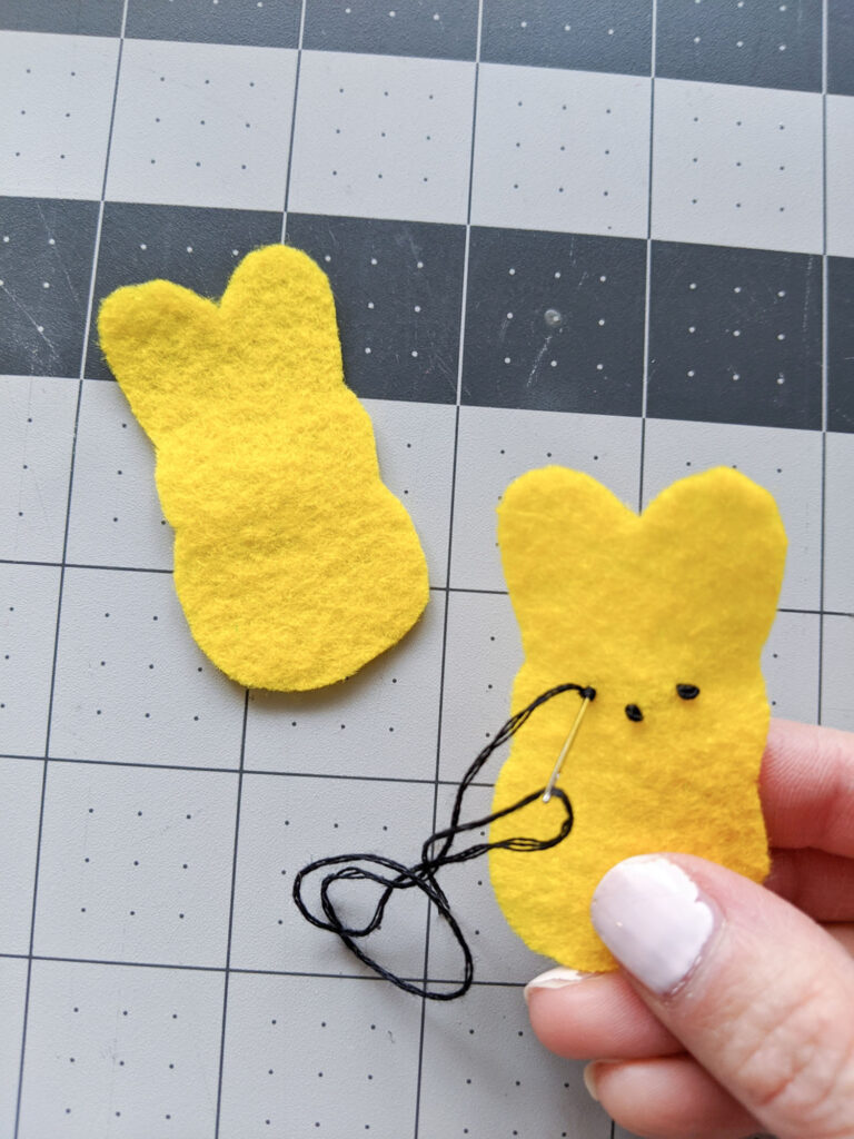 Sewing the eyes and nose to the Peeps bunnies using black embroidery floss.