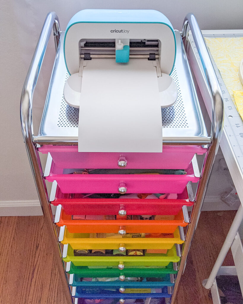 Cricut Joy on top of rainbow craft cart.