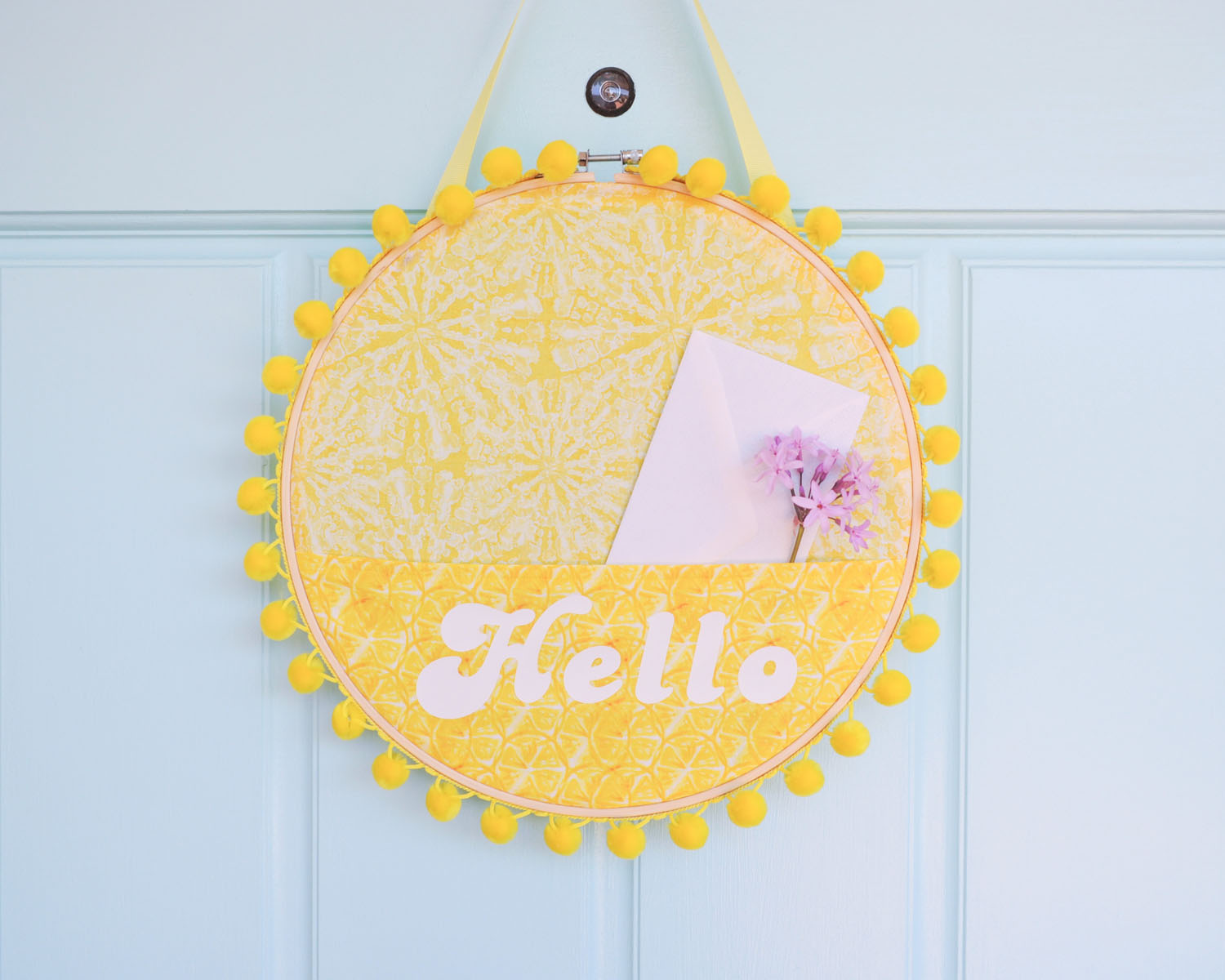 Sunshine front door wreath holding envelope and flower