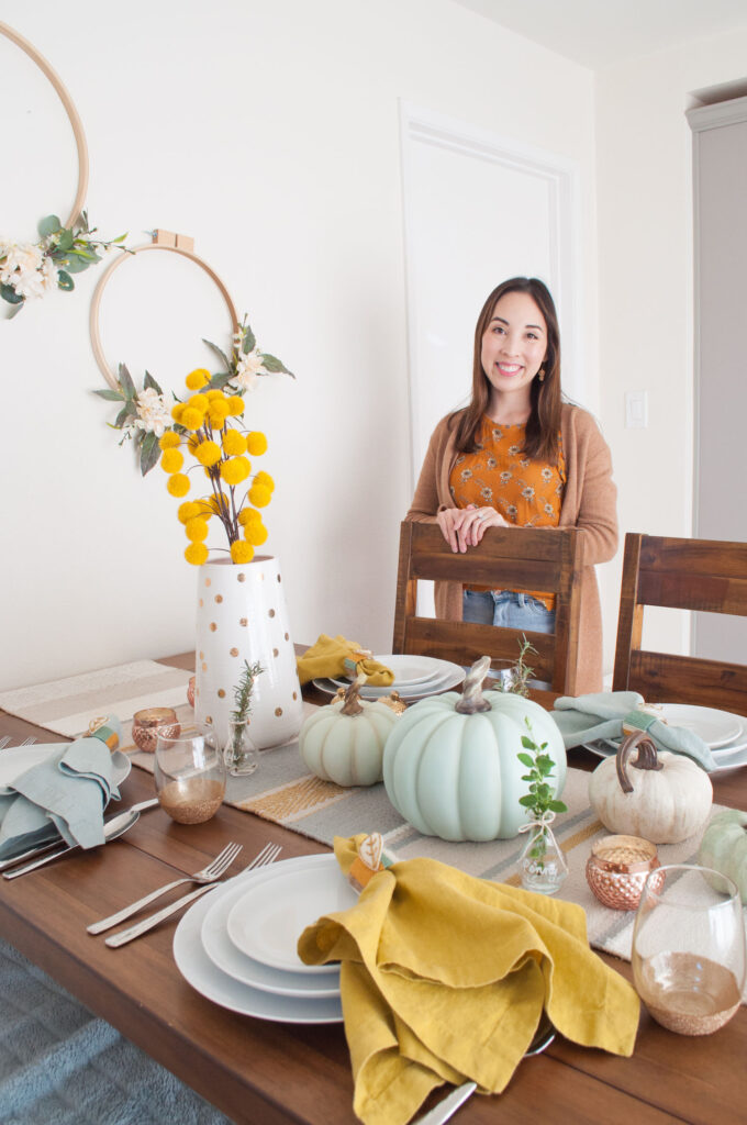 Blaire from Freshly Fuji standing behind chair of her Thanksgiving table.