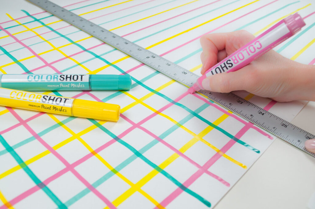 Showing how to use COLORSHOT paint markers to draw a grid pattern on white gift wrap.