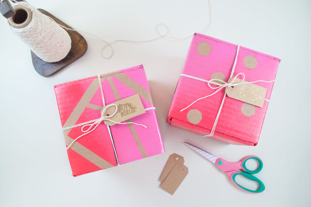 First holiday gift wrap hack finished. Two cardboard boxes spray painted in a gradient pattern using COLORSHOT spray paint. The boxes are tied with string and brown gift tags are attached.