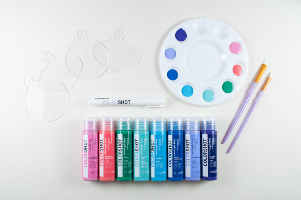 Photo of materials needed for the third gift wrap hack: Clear acrylic ornaments, COLORSHOT acrylic paints, paint brushes, paint palette and white chalk marker