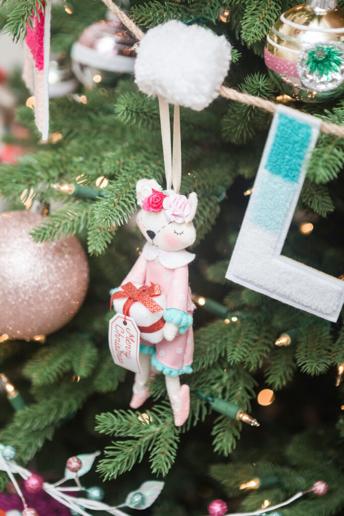 Close up of fox ballerina ornament. The fox is dressed in pink and is holding a present. 