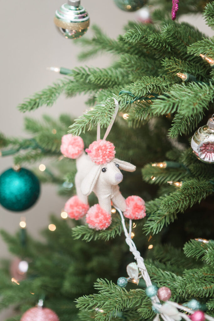 Close up of poodle dog ornament with coral pom poms.