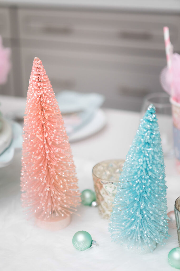 Close up of pink and light blue bottle brush trees on white faux fur table runner.