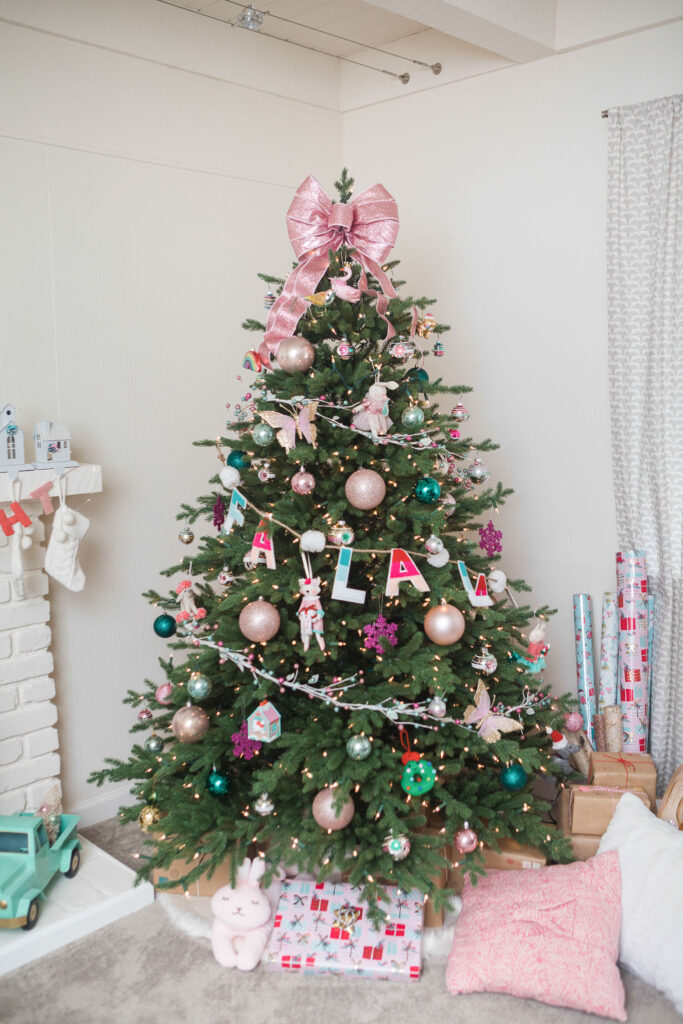 Pink Christmas theme Christmas tree with colorful ornaments and a giant pink bow as it's topper. 