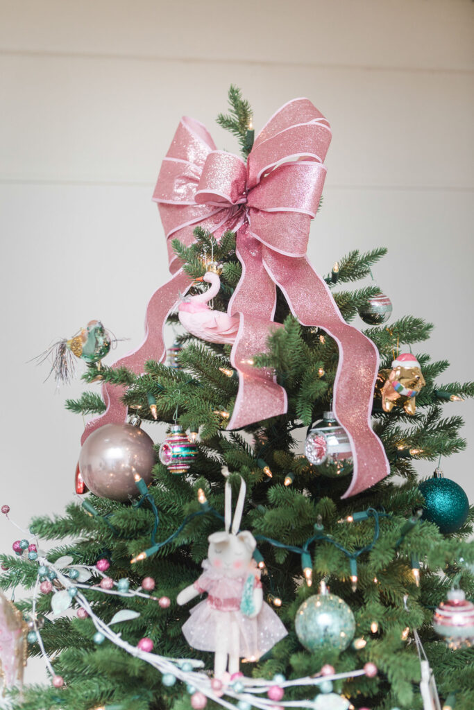 Christmas tree with a giant pink glitter bow as the tree topper.