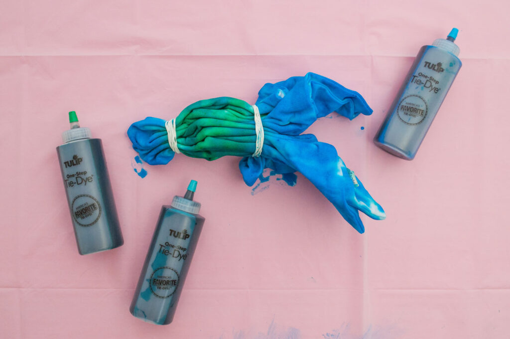 Pillow cover with green, blue and turquoise bottles of Tulip Tie Dye.