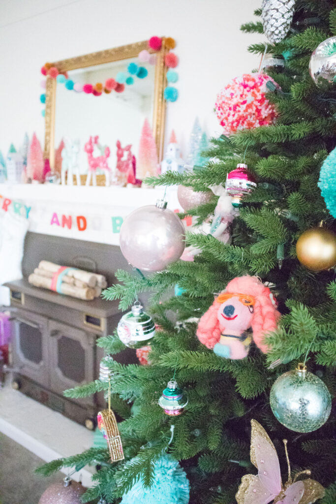 Close up of Christmas tree featuring a variety of ornaments - pom poms, shiny balls, shiny brites, felt dogs, etc.
