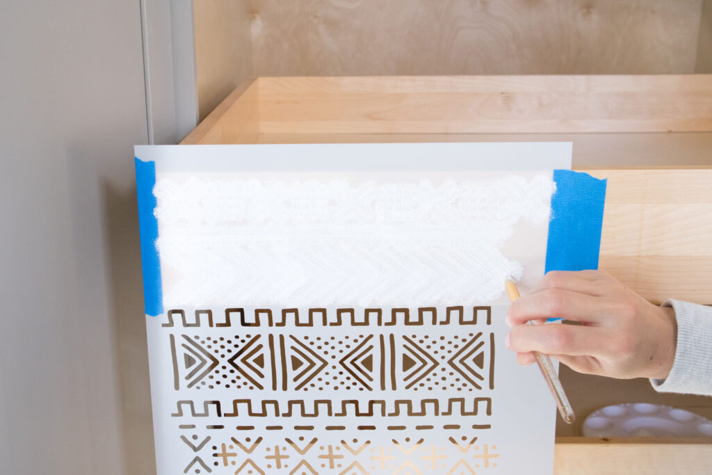 Top pull out drawer with stencil placed on top. Blaire is applying Colorshot Marshmallow (white) acrylic paint using a stencil brush