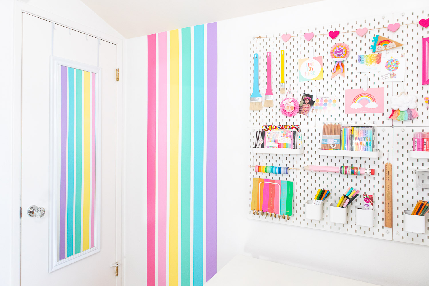 Photo of rainbow stripe wall with Blaire's colorful pegboard on the right side.