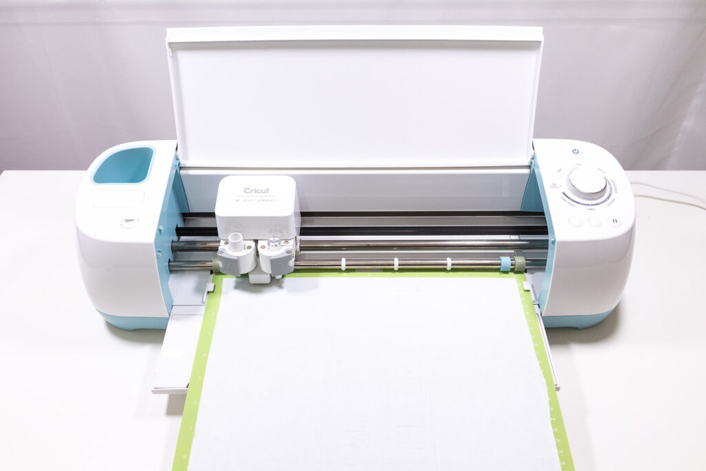 White freezer paper placed on green mat, loaded into Cricut Explore Air machine.