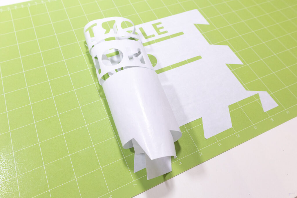 Freezer paper stencil is being peeled of green Cricut mat.