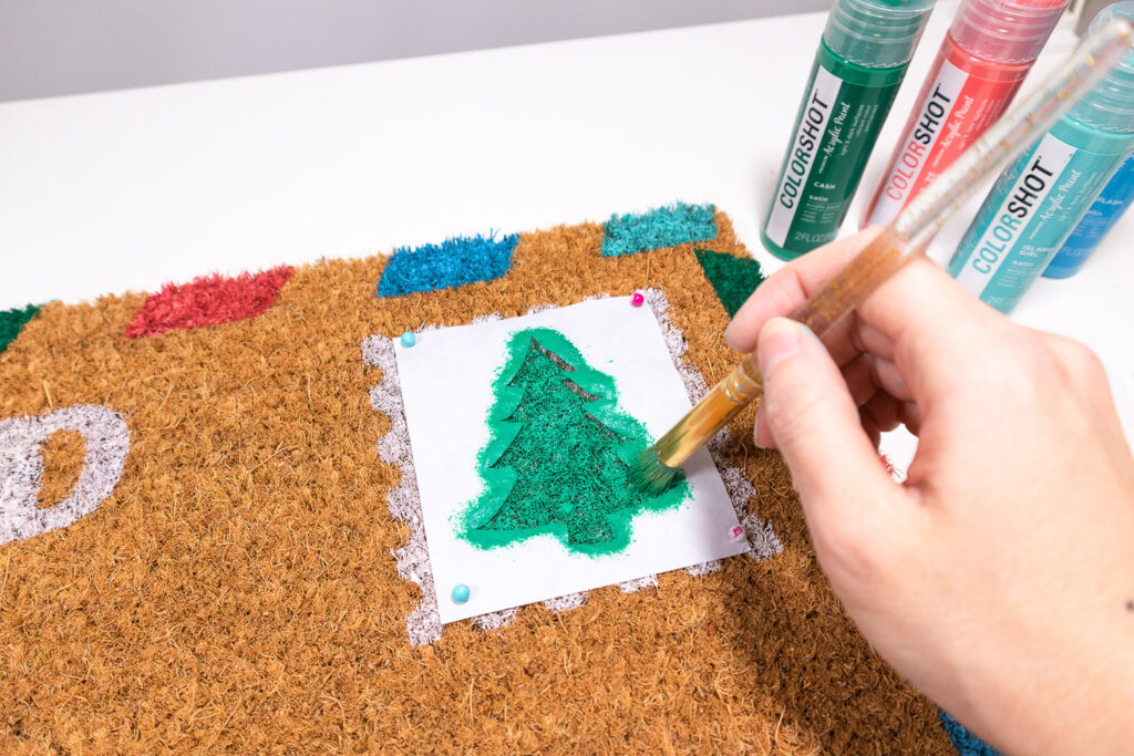 Applying green paint to tree stencil.