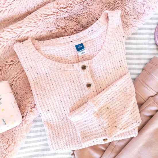 Blush pink loungewear, mug, portable speaker, and faux fur throw.