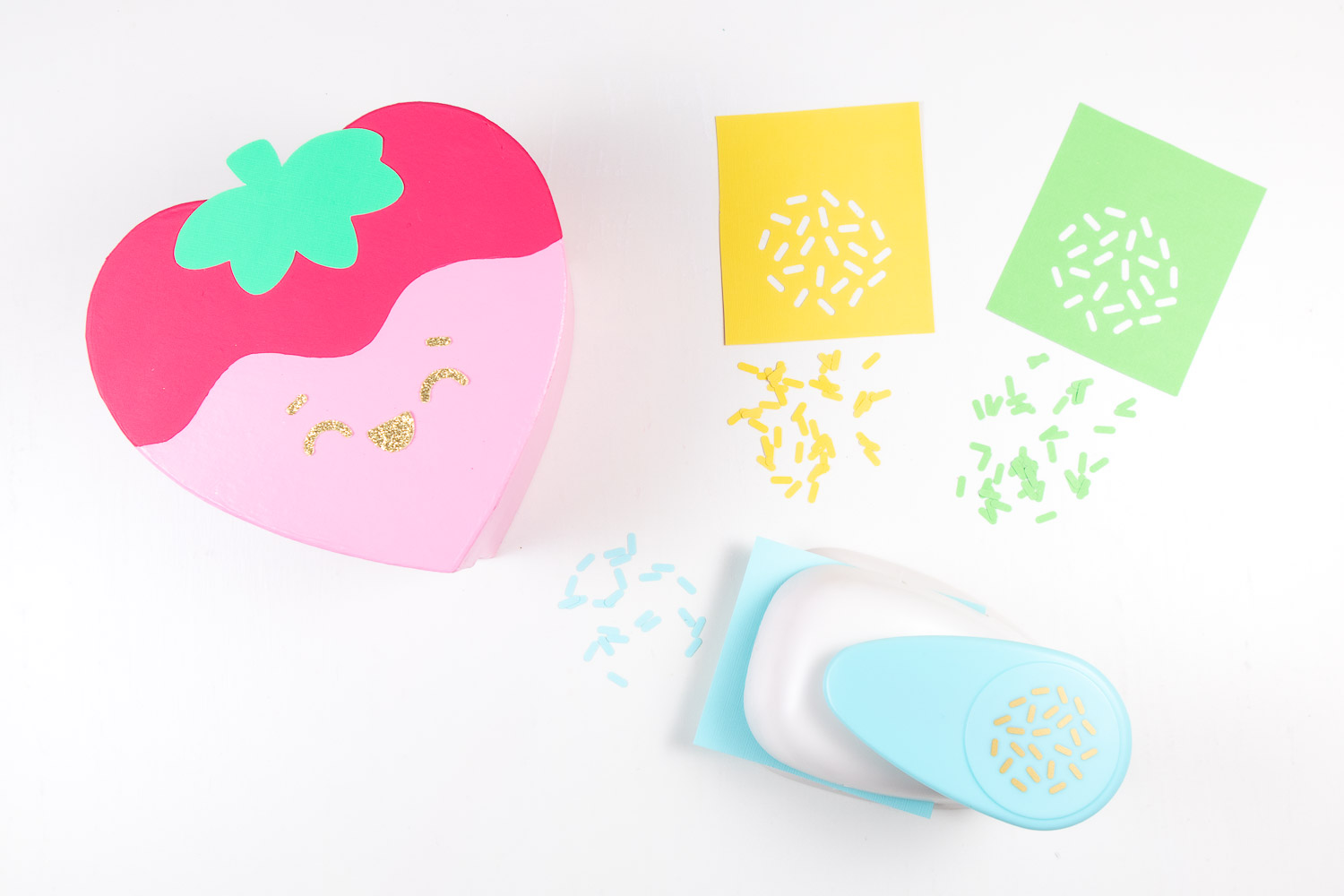 Cutting out colored sprinkles using sprinkles paper punch. Yellow, light green and light blue sprinkles are shown.