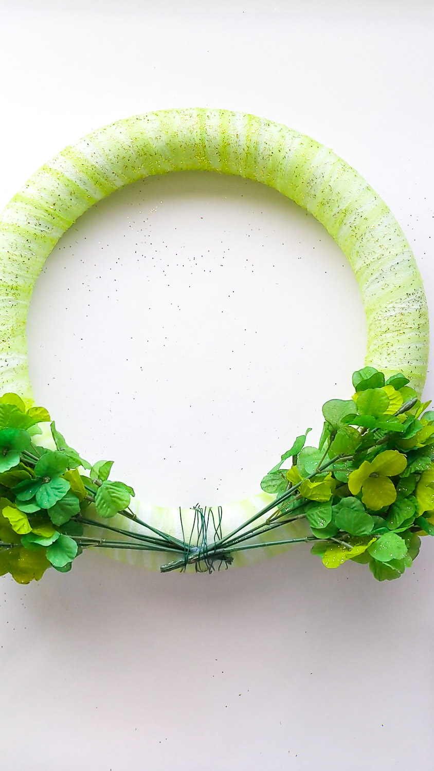 Two shamrock sprigs are attached to the base of the wreath using floral wire.