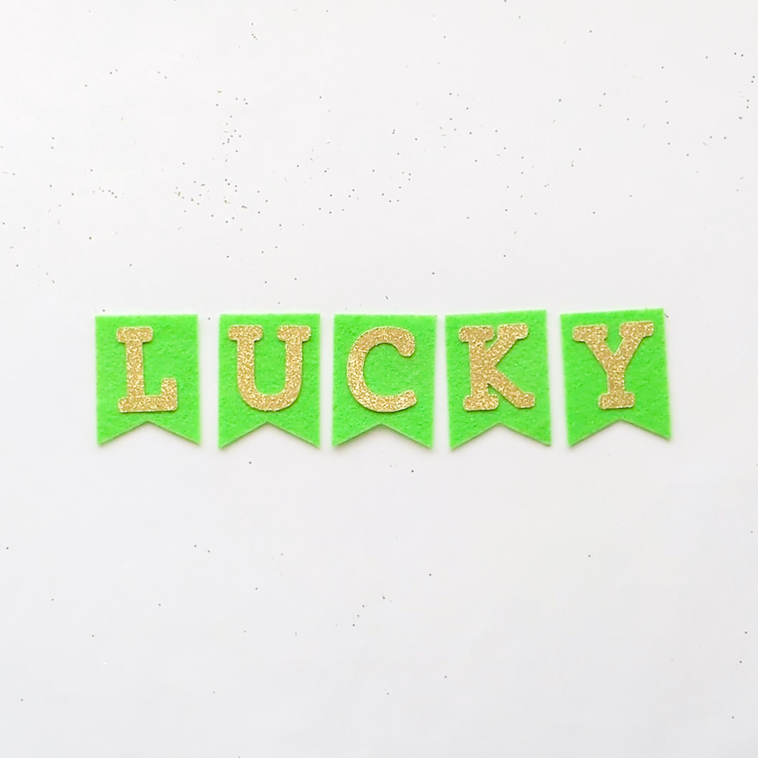 Lime green felt pennants with attached gold glitter letters spelling "LUCKY".