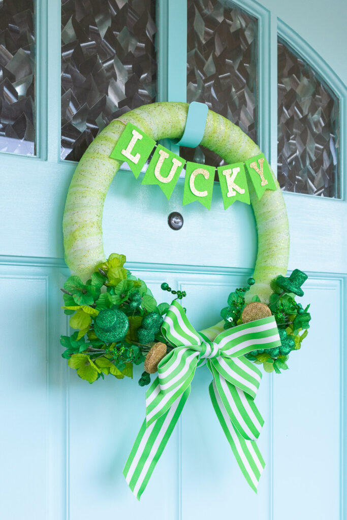 Green St. Patrick's Day wreath hug on light blue door.
