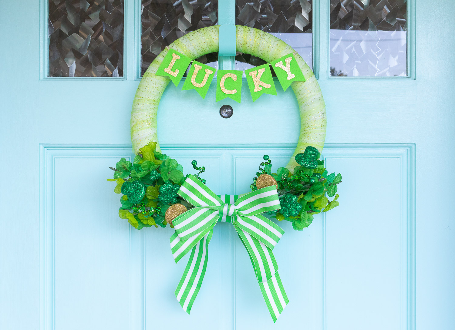 Bright green St. Patrick's Day wreath hung on blue door.