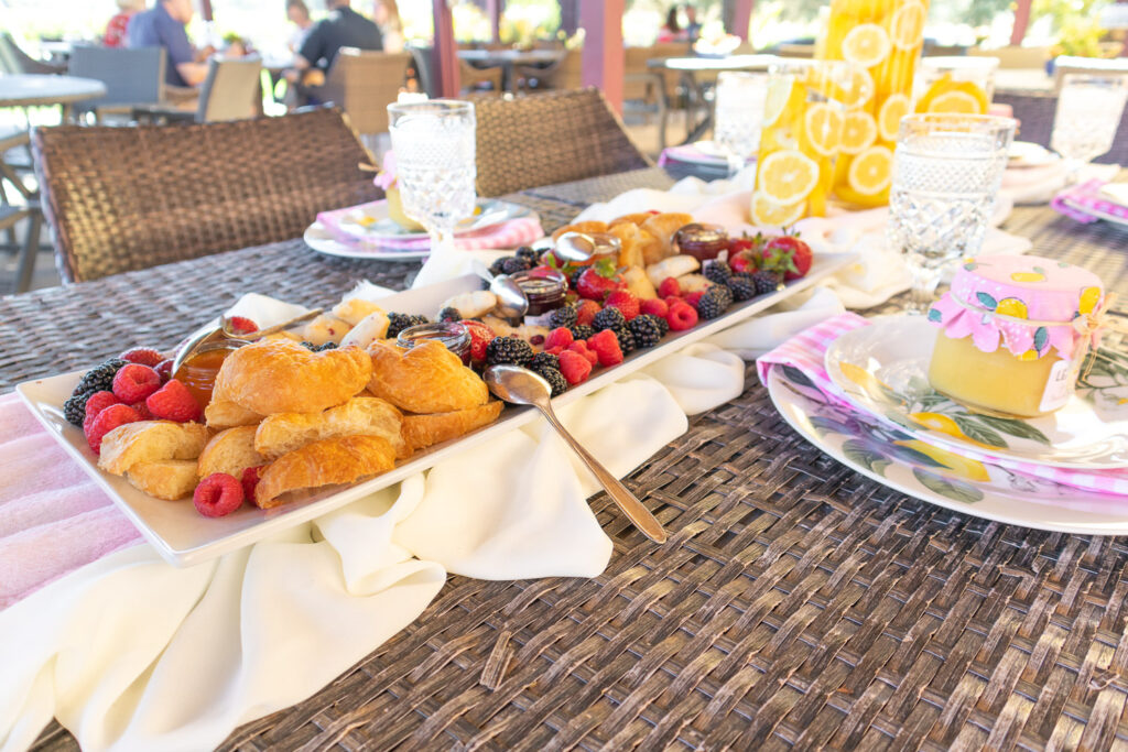 A large fruit and pastry tray is placed in the center of a patio table.