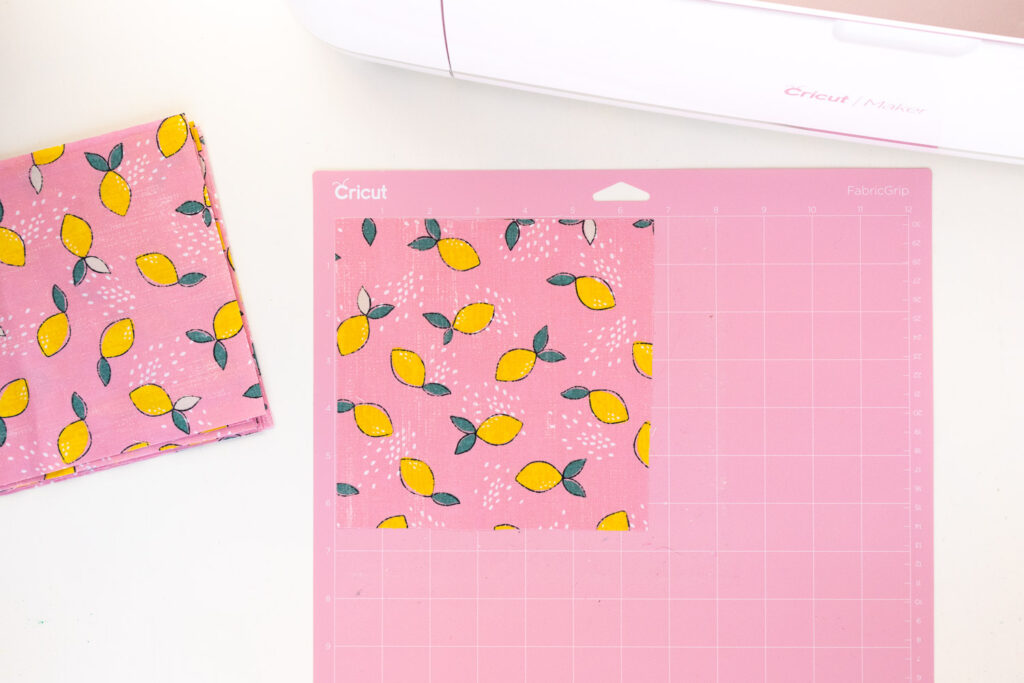 Placing fabric squares onto a pink FabricGrip mat in preparing for cutting with Cricut machine.