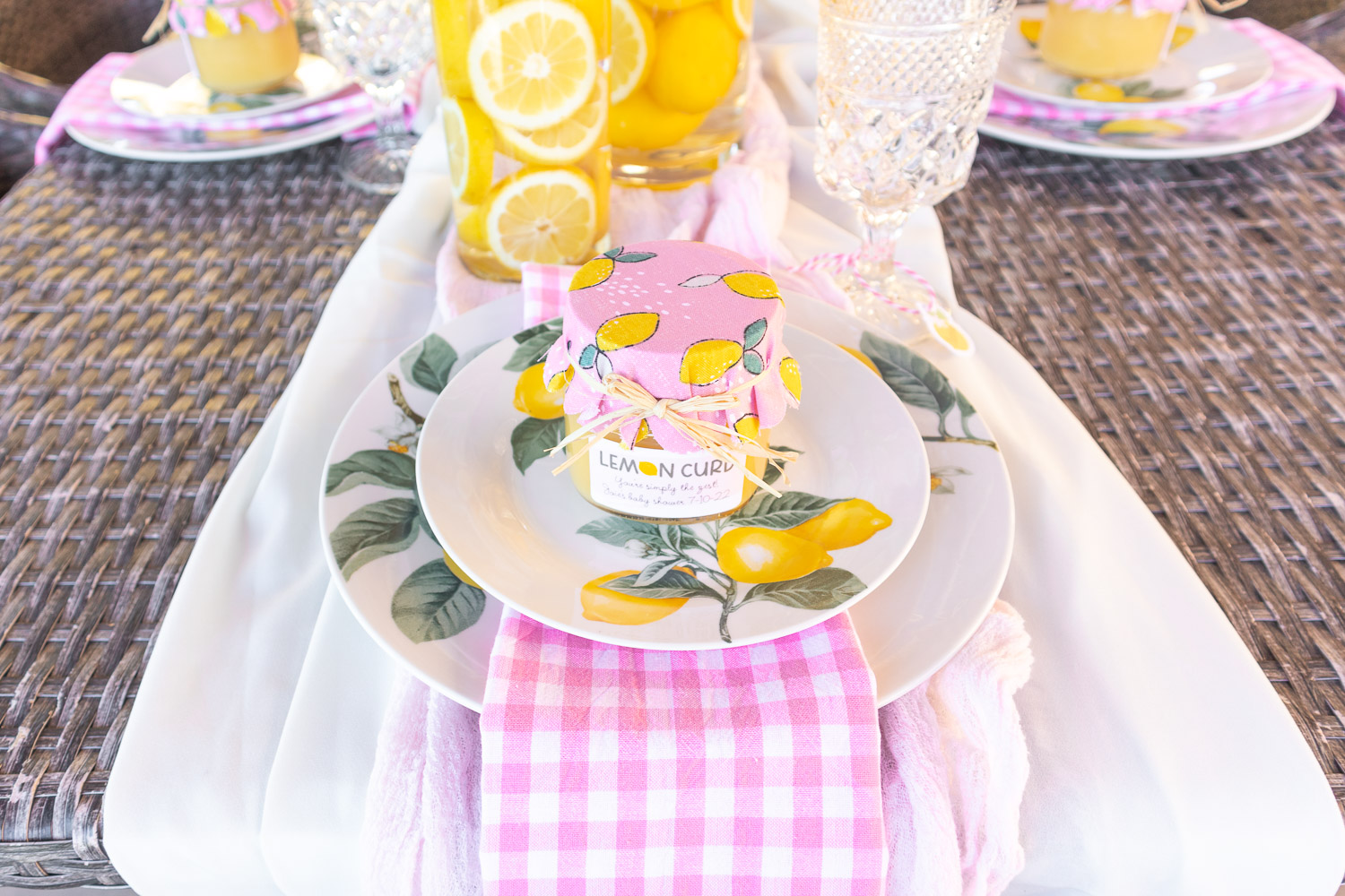 Pink and yellow baby shower place setting featuring lemon plates, pink gingham napkin and homemade lemon curd favors.