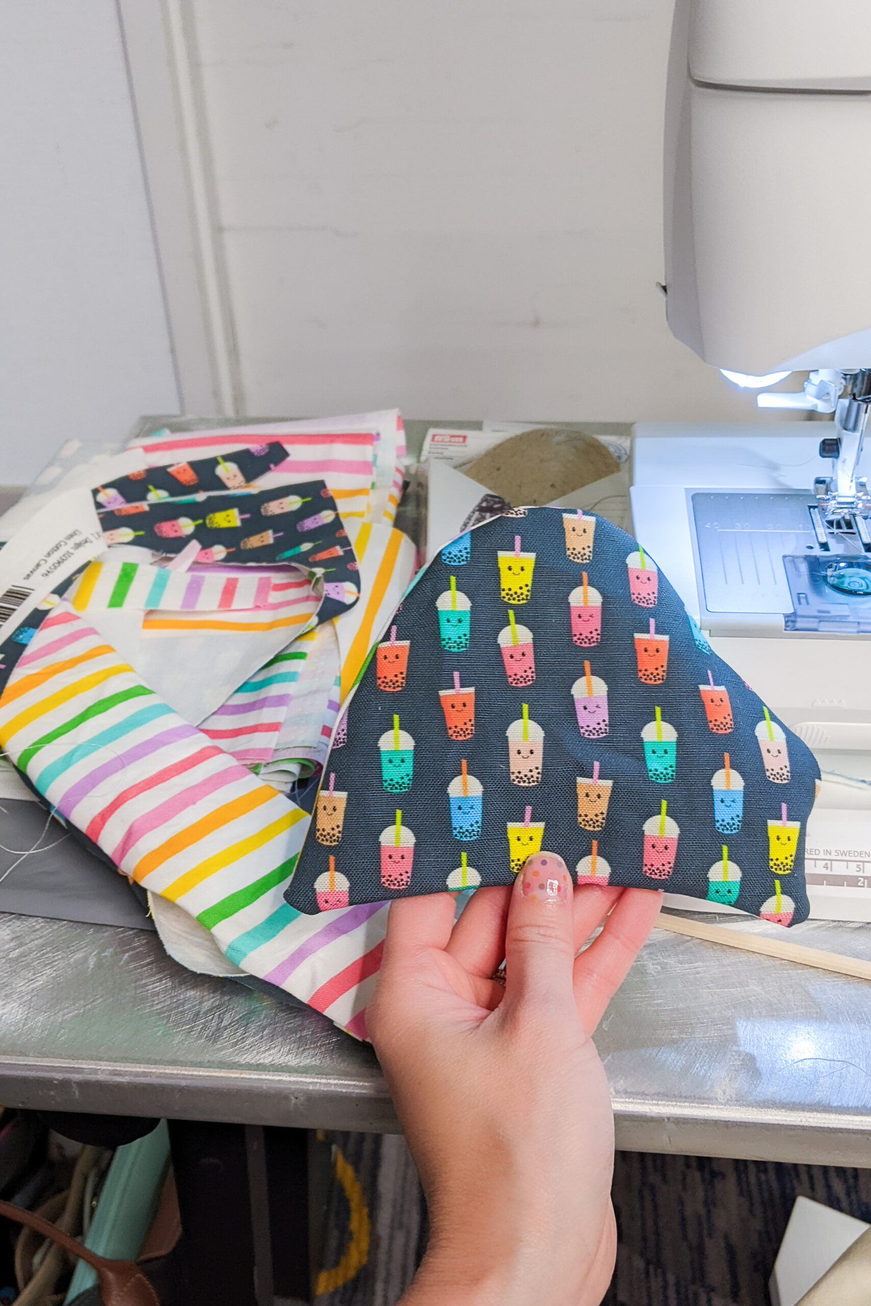 Holding up part of the top of the shoe. The fabric is navy with rainbow bubble teas printed all over.